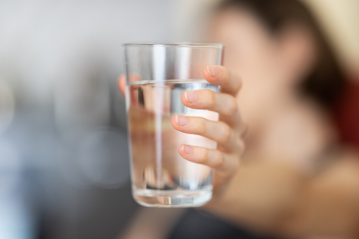 Woman holding a glass of water.