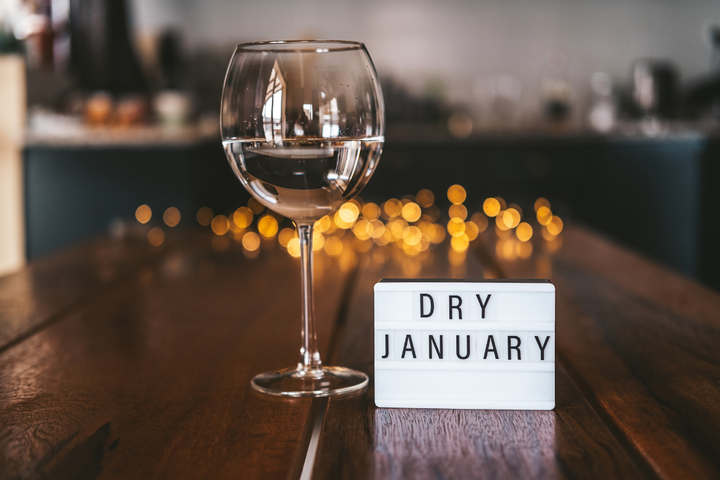glass of water beside sign reading dry january on wooden table