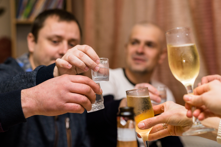 Group of friends raising glasses during a toast as part of their drinking every weekend routine.