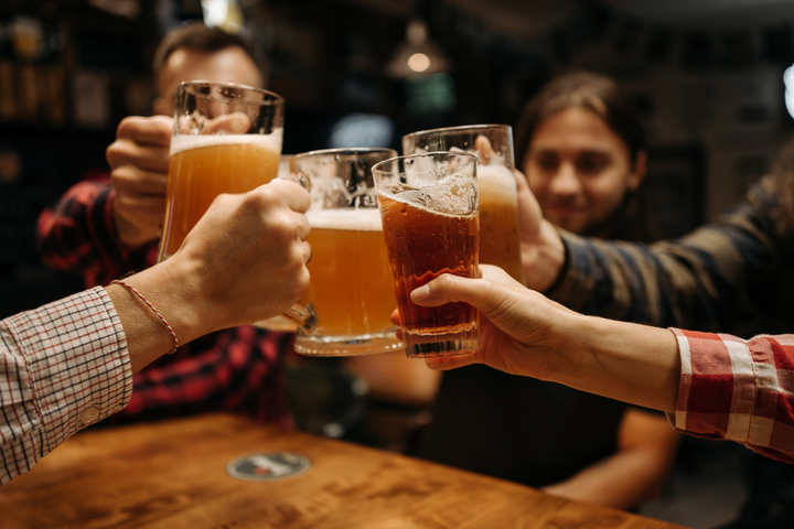 Group of friends clinking beer glasses, highlighting the lifestyle context of supplements for drinkers.