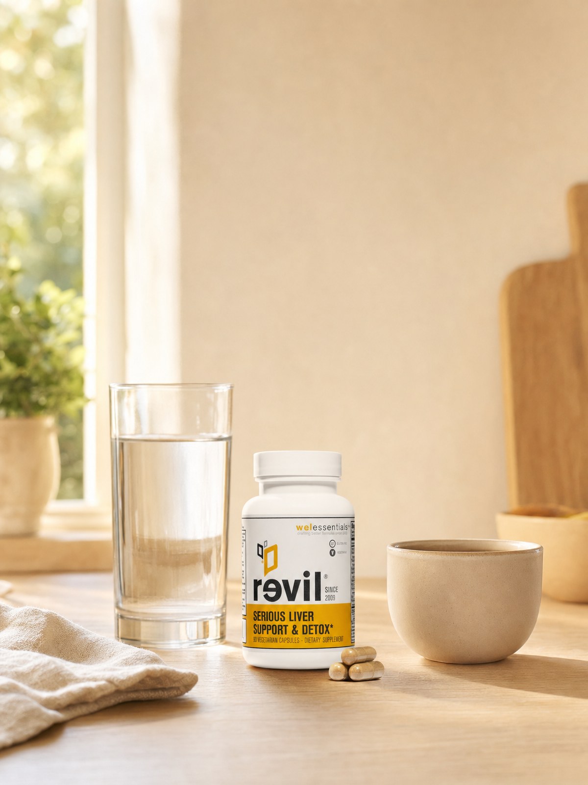 A woman at a sunlit kitchen counter with her Revil bottle, coffee and water.